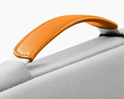 دستهٔ چرمی نارنجی روی یک کاور لپ‌تاپ خاکستری Tomtoc
